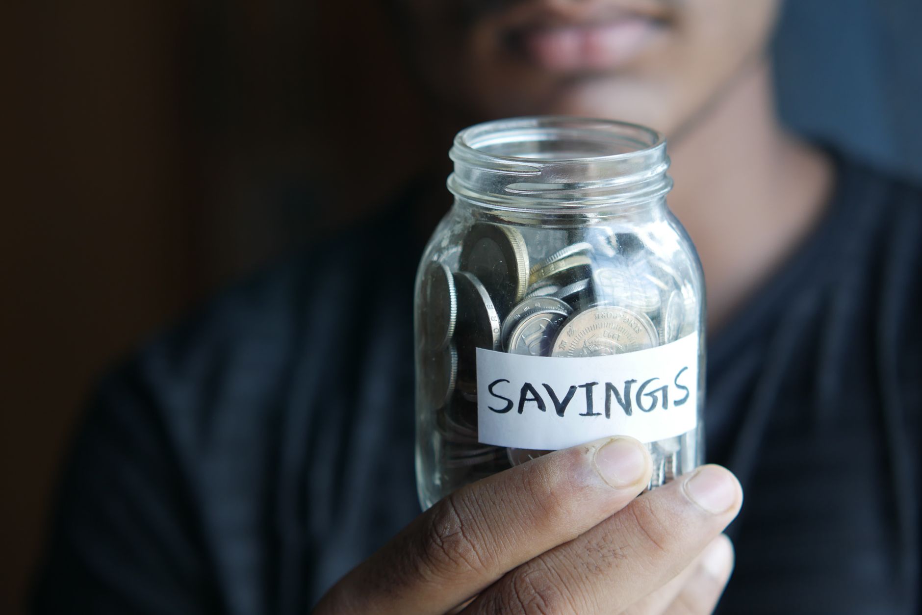 手中拿著標明Savings的儲蓄罐