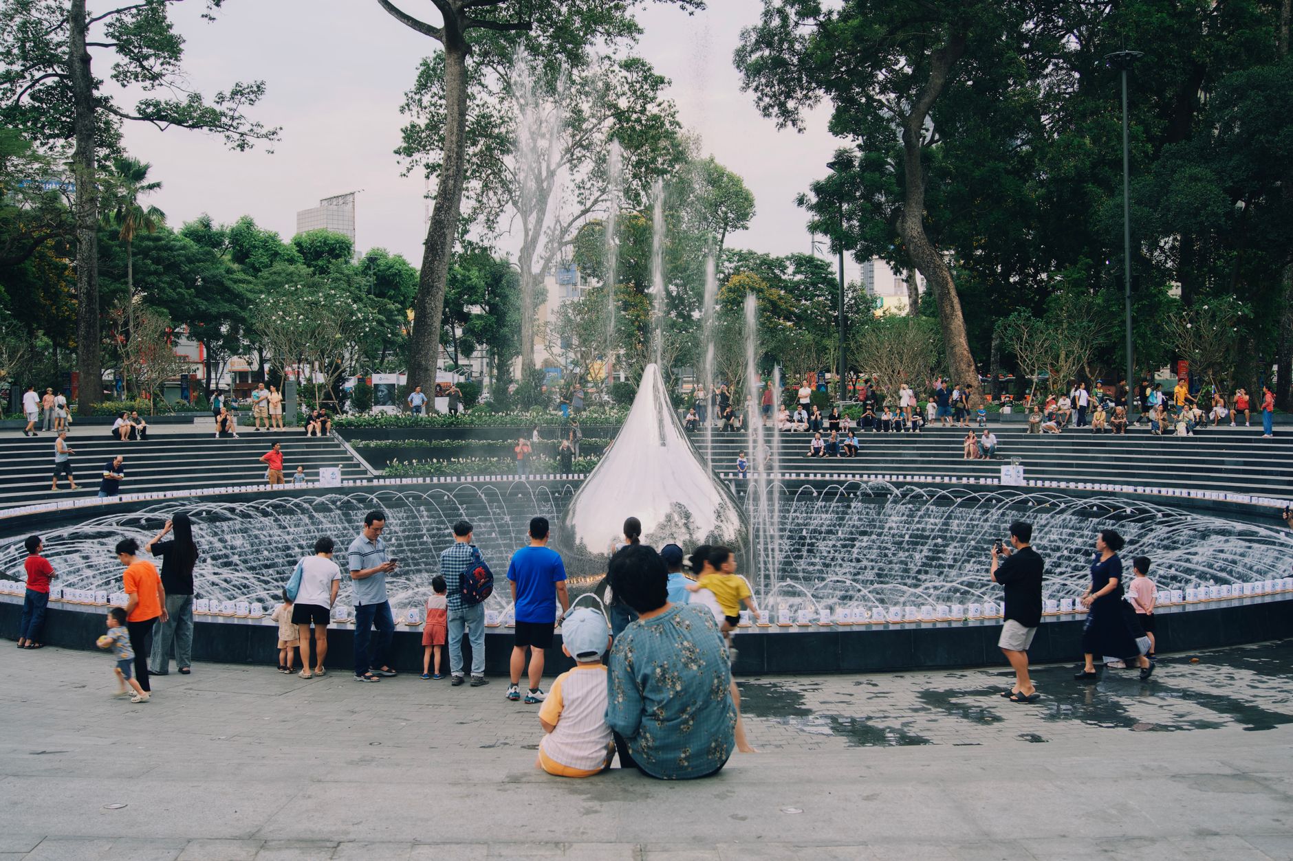 一家大小在公園噴泉池旁享受戶外時光