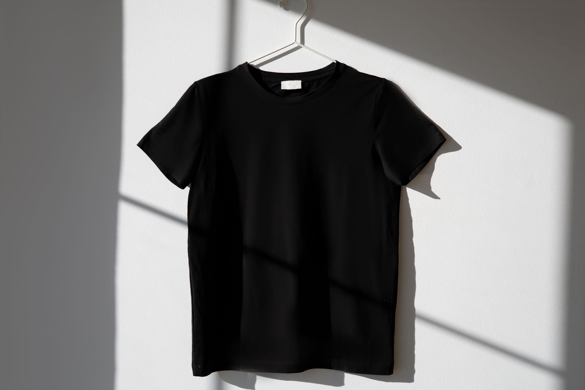 黑色淨色Tee 掛在衣架上的簡約畫面